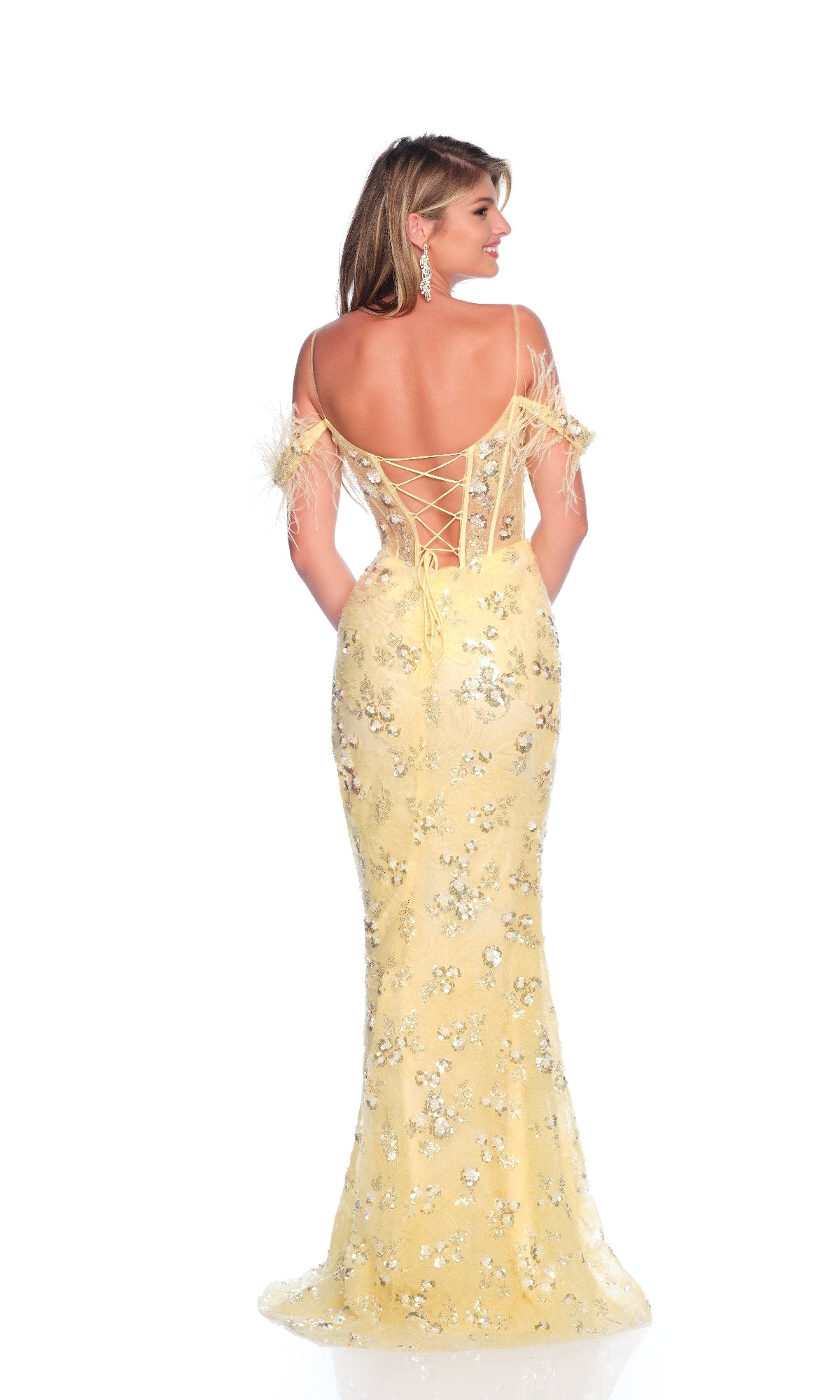 A woman faces away wearing the Dave & Johnny 12095 pastel yellow prom dress, featuring feather off-the-shoulder straps, floral sequins, an open lace-up back, and a fitted floor-length silhouette.